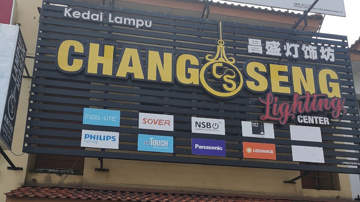 Black slatted signboard reading Chang Seng Lighting Center with Chinese characters and eight brand logo panels