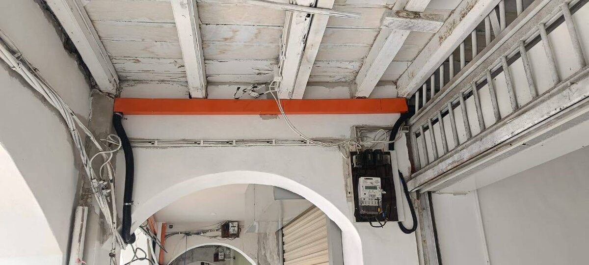 Five-foot way ceiling with a new orange cable trunking running to a wall-mounted electricity meter board, black flexible conduits at each end