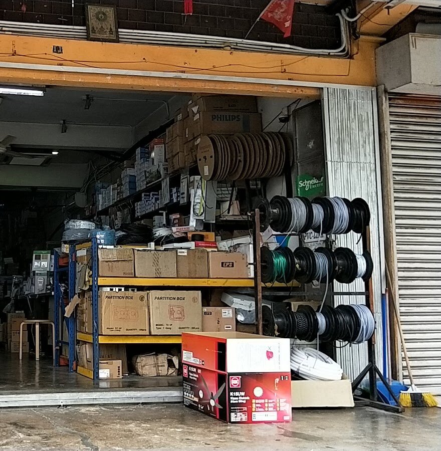 Open shopfront with racks of cable reels, cardboard partition boxes and shelves of electrical accessories under a Schneider Electric sign