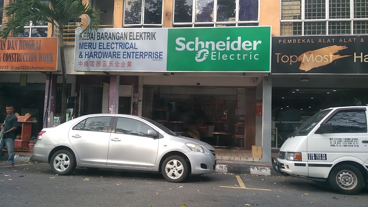 Row of shoplots with a signboard reading Kedai Barangan Elektrik Meru Electrical & Hardware Enterprise beside a green Schneider Electric panel