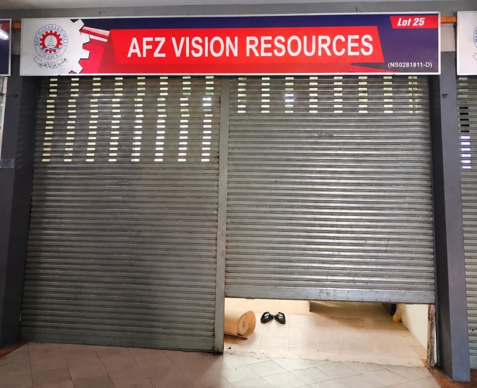 Shop unit with a red and navy "AFZ VISION RESOURCES" signboard marked "Lot 25" and "(NS0281811-D)" above two grey roller shutters, one partly raised over a tiled floor