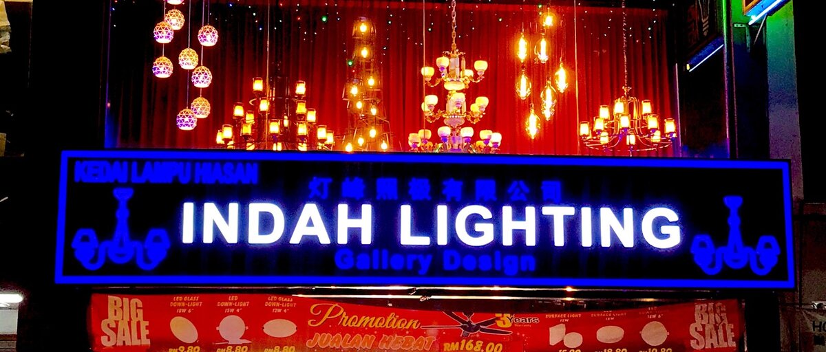 Illuminated blue Indah Lighting signboard with chandeliers lit in the window above
