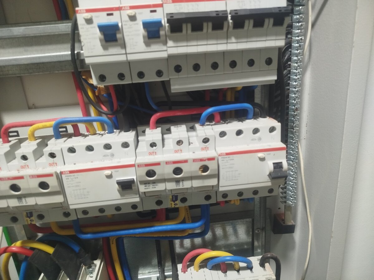 Open three-phase distribution board with ABB residual current circuit breakers and miniature circuit breakers, with red, yellow and blue wiring