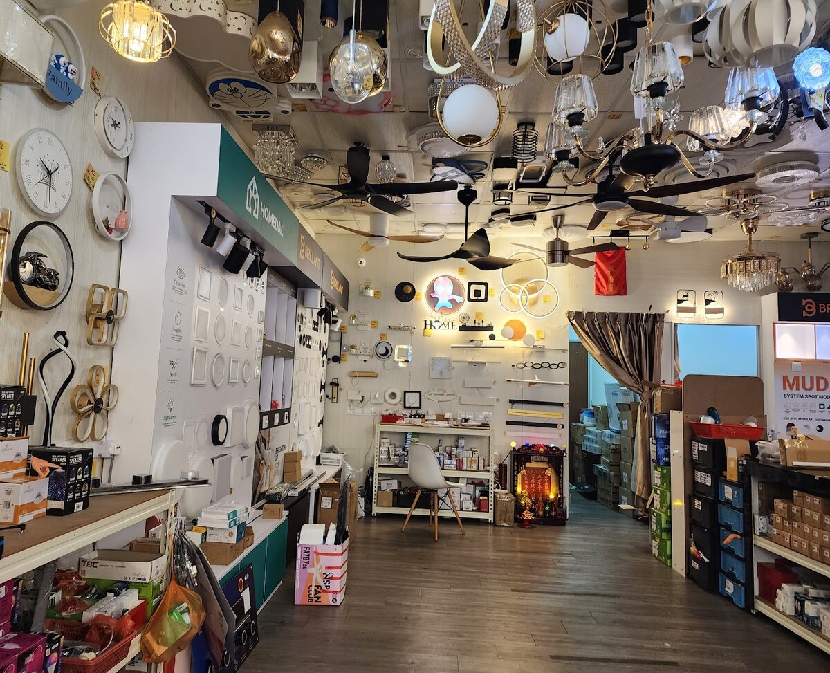 Shop interior with wall lights and clocks on the left wall, pendants and ceiling fans overhead and shelves of boxed stock