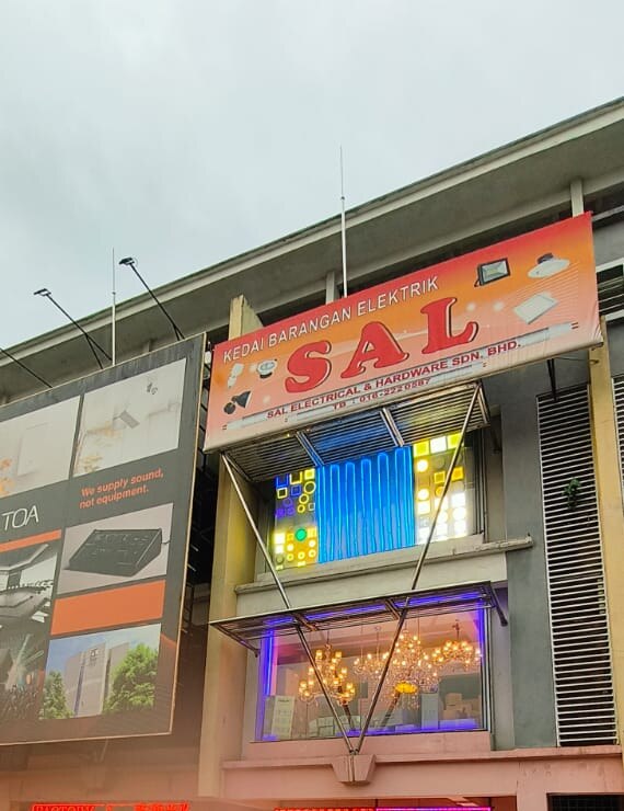 Multi-storey shop with an orange SAL signboard, a lit glass panel and chandeliers in the first-floor window