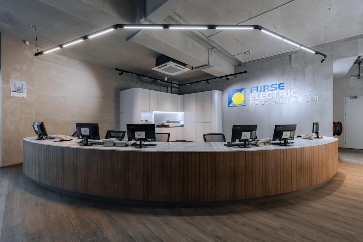 Long curved wooden counter with computer screens under a Furse Electric wall sign