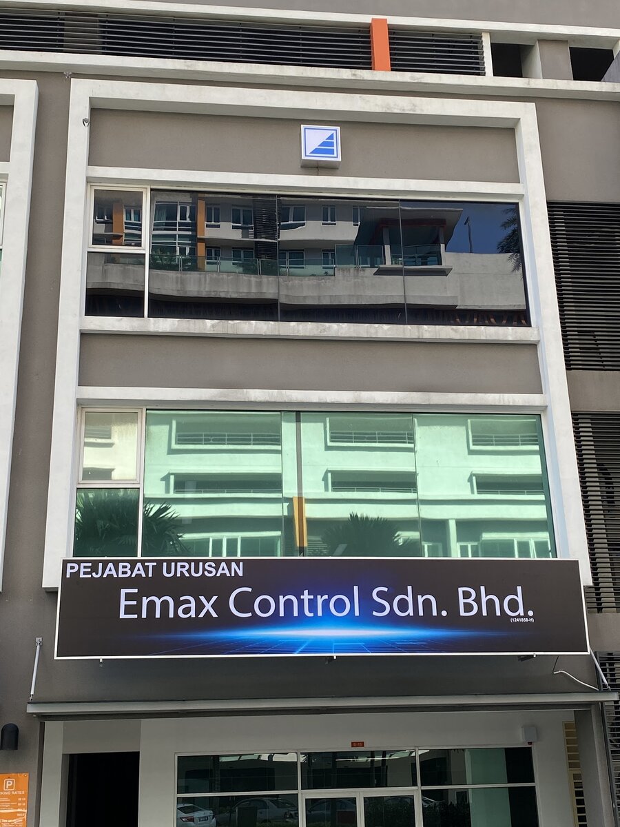 Shop-office block with a dark "Pejabat Urusan Emax Control Sdn. Bhd." signboard above the ground-floor glass front