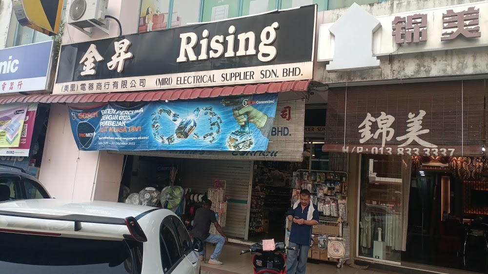Shopfront with a large black Rising signboard in English and Chinese above an open entrance with fans and electrical goods on display