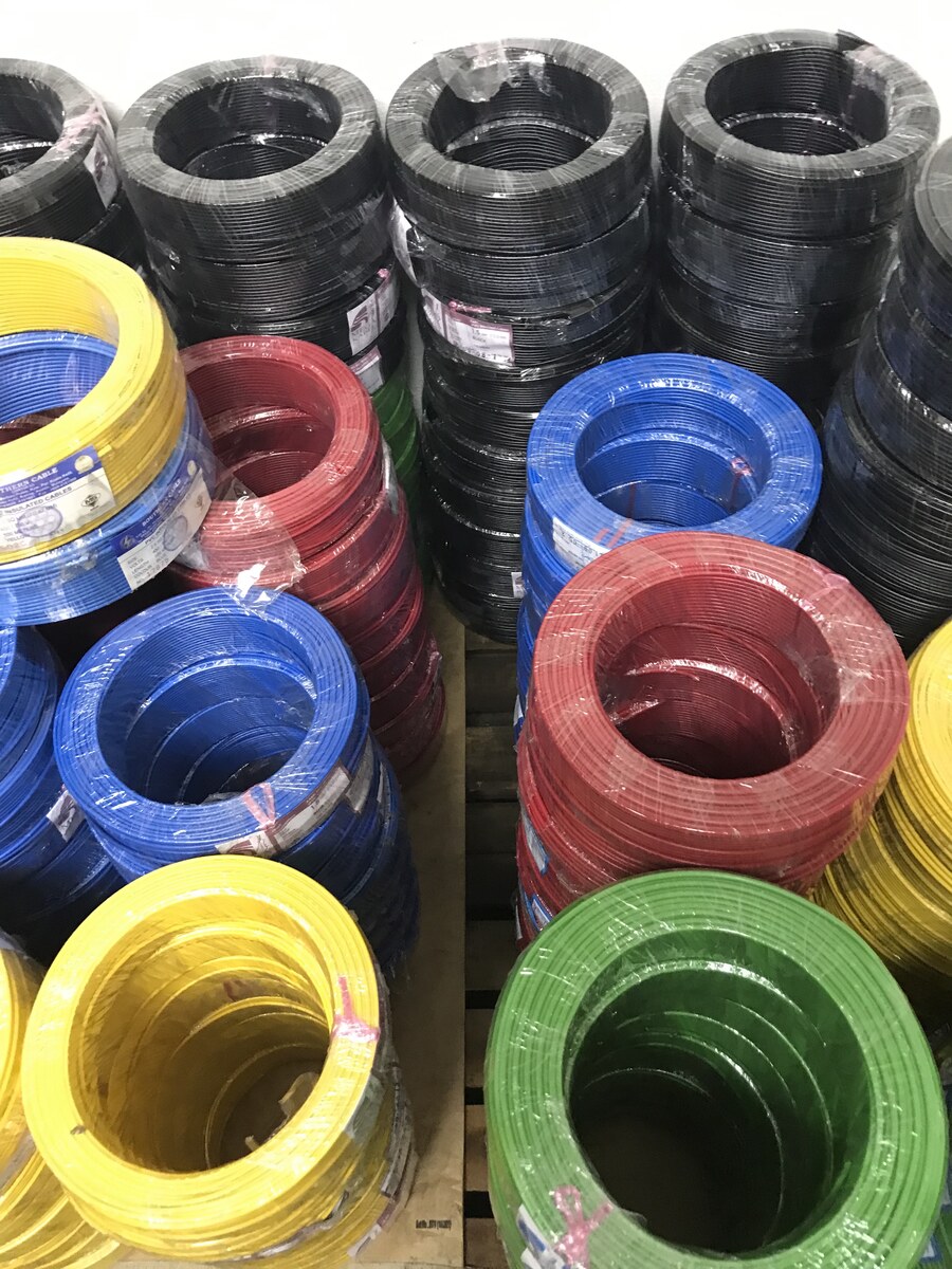 Stacks of yellow, blue, red, green and black cable coils in plastic wrap on a wooden pallet