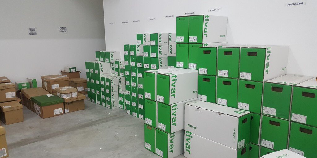 Room stacked with green-and-white Schneider Altivar drive boxes and brown cartons