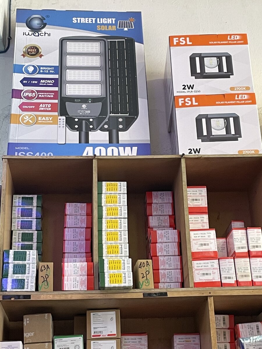 Wooden pigeonholes holding stacks of small green, red and white breaker boxes, with boxed solar street and pillar lights on top