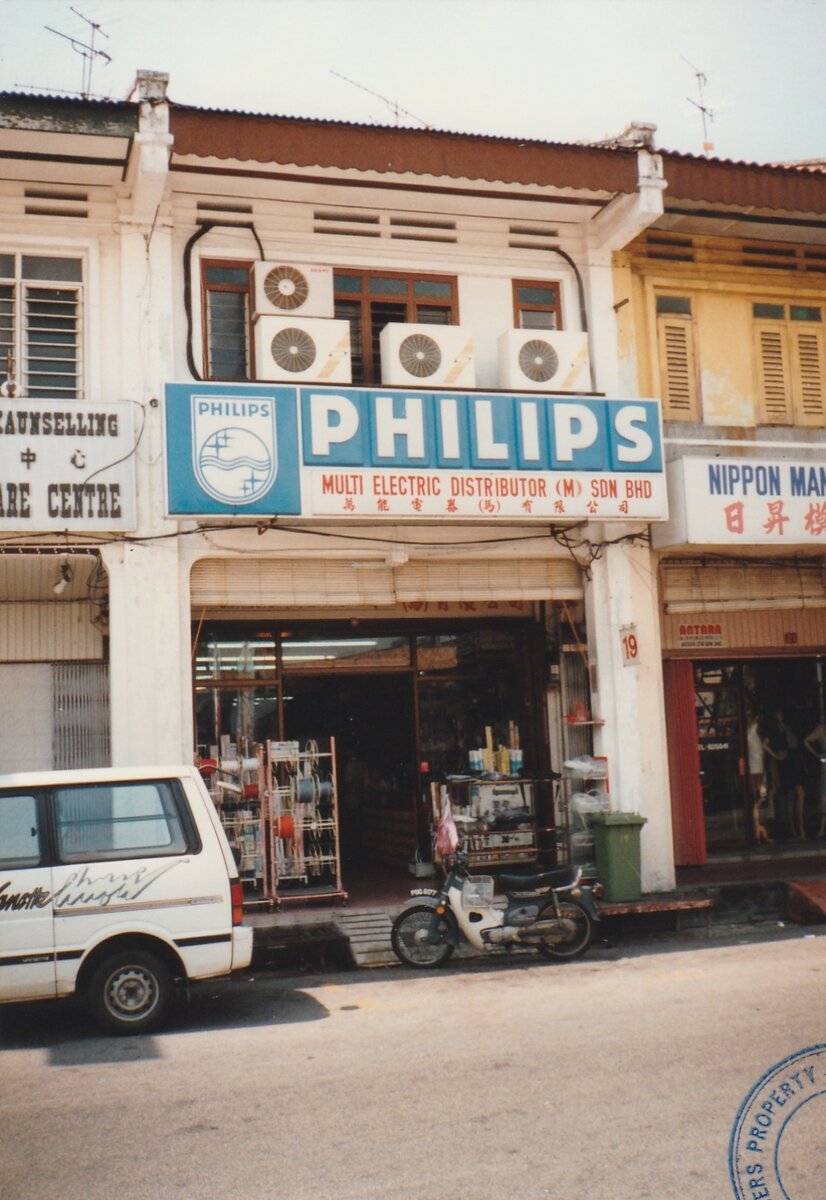 Old colour photo of a two-storey shophouse with a blue Philips signboard reading Multi Electric Distributor (M) Sdn Bhd and door number 19