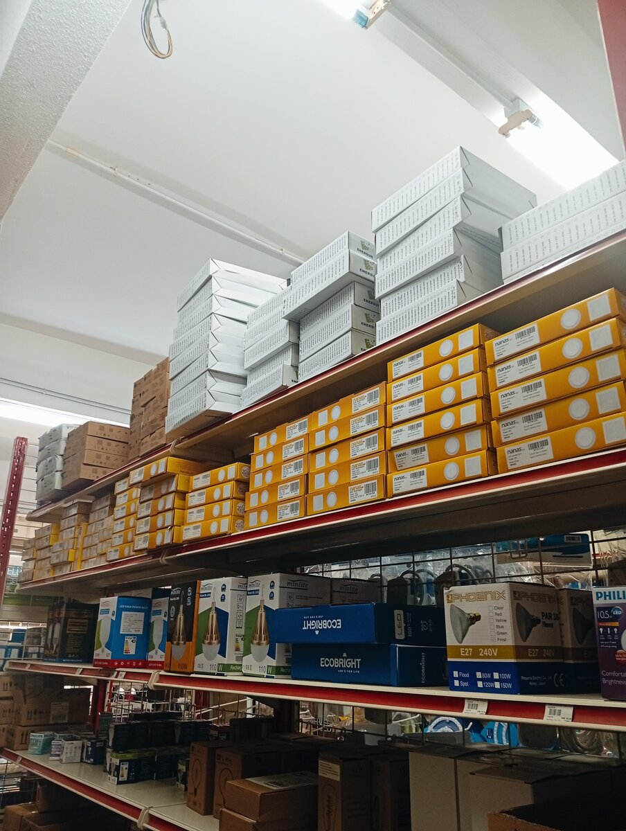 Store shelves with yellow Nanas downlight boxes, white Enersun boxes and boxed LED bulbs and PAR38 lamps