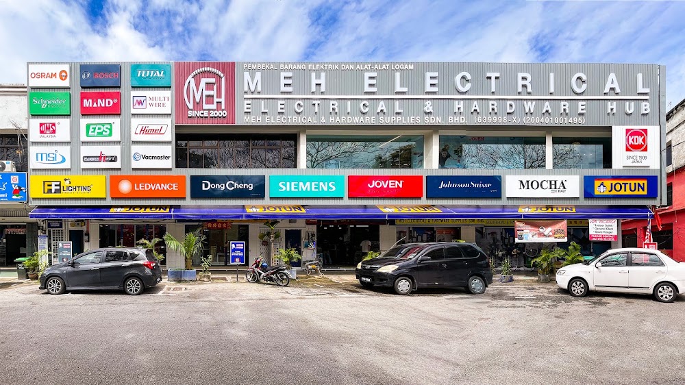 Wide shopfront with a grey MEH Electrical signboard and rows of brand logos above a blue awning