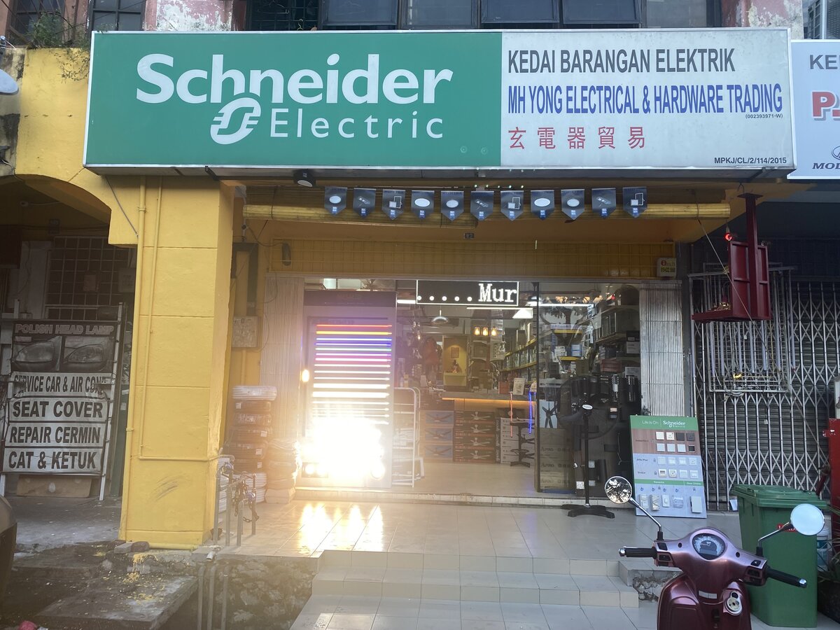 Shopfront with a green Schneider Electric and white MH Yong Electrical & Hardware Trading signboard, glass doors, cable coils and display stands