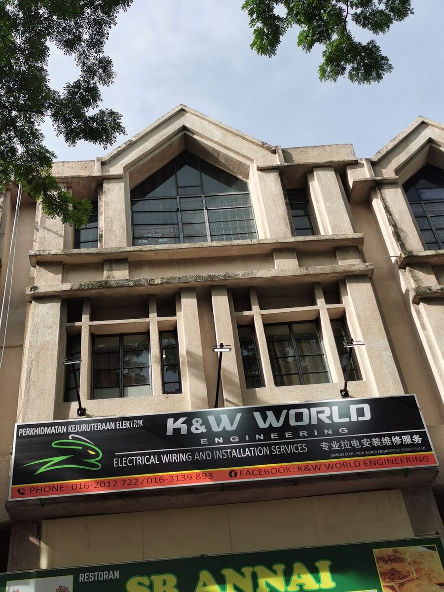 Black signboard reading K&W World Engineering, electrical wiring and installation services, with phone numbers 016-2012 722 and 016-3139 893, above a restaurant sign