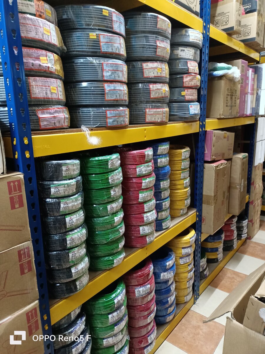 Steel shelving stacked with grey flexible-cord coils above black, green, red, blue and yellow single-core cable coils