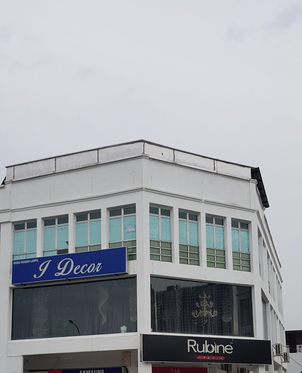 White three-storey corner block with a blue "Kedai Hiasan Lampu I Decor" sign above dark display windows