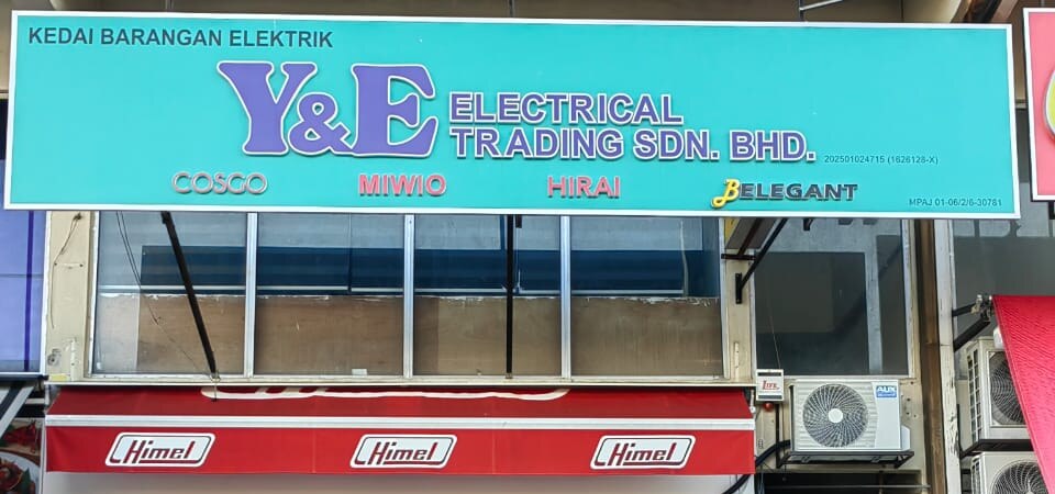 Turquoise shop signboard reading Kedai Barangan Elektrik, Y&E Electrical Trading Sdn Bhd, with four brand names, above a red awning printed with the Himel logo three times