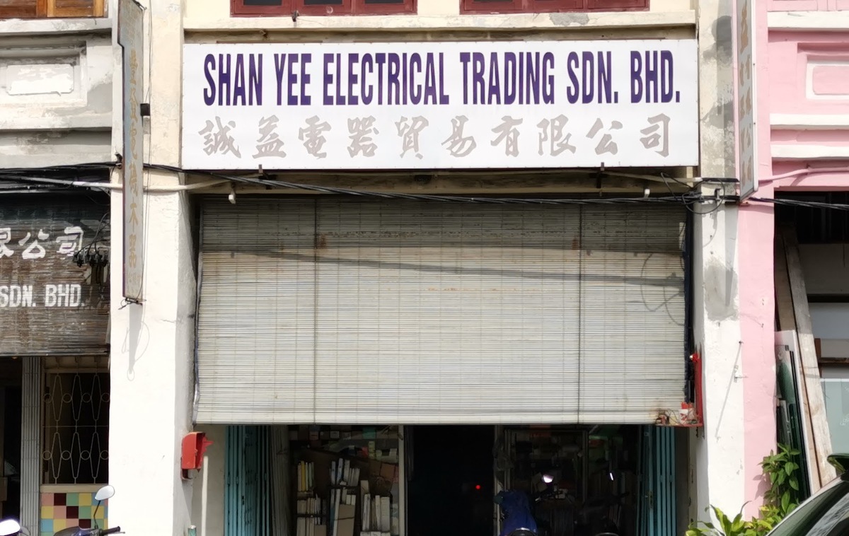 Old shophouse with a white signboard reading Shan Yee Electrical Trading Sdn. Bhd. above a half-raised bamboo blind and an open shop entrance