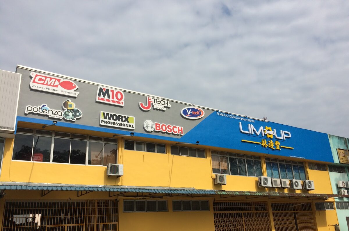 Long yellow two-storey industrial building with a blue Lim-up 林連豐 signboard and tool-brand logos