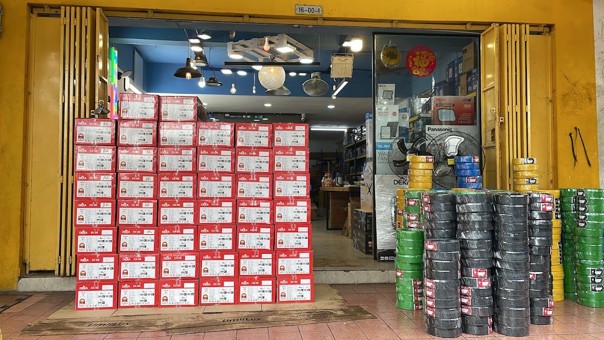 Open shopfront with a wall of red water heater boxes and stacks of yellow, green and black cable coils in front