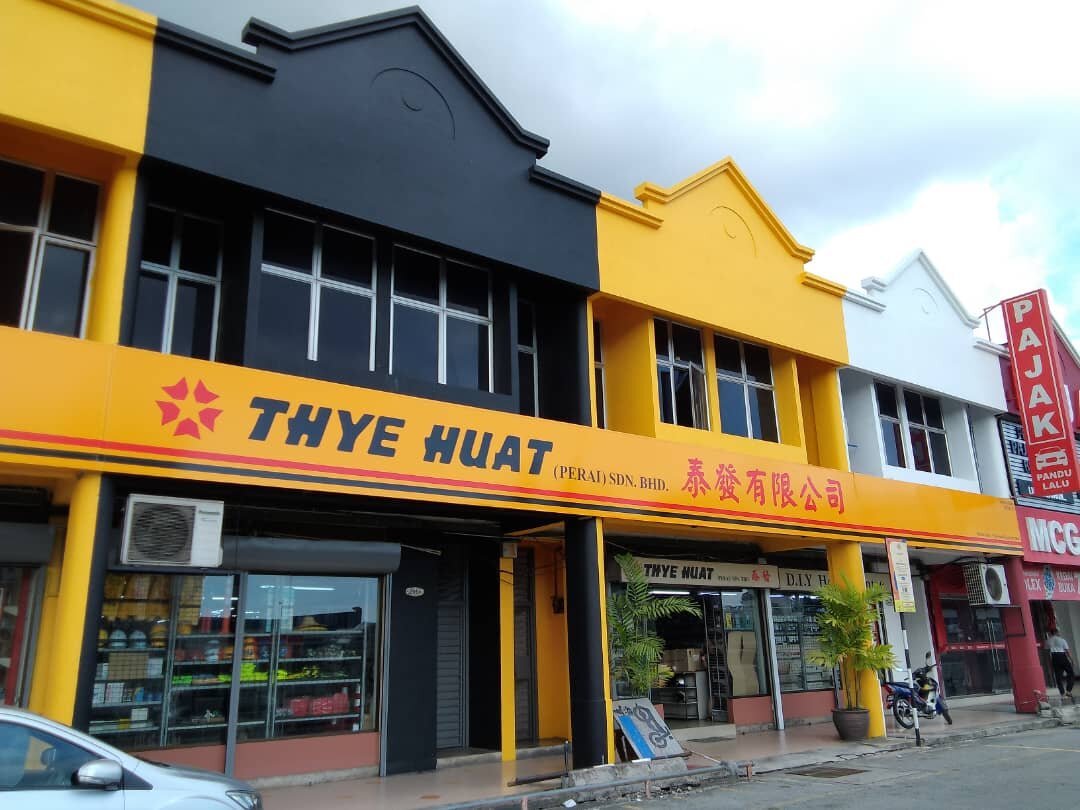 Two-storey shophouse painted yellow and black with a Thye Huat (Perai) Sdn Bhd signboard and glass shopfront