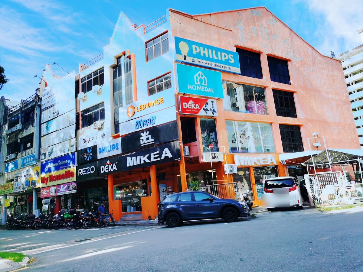 Orange and white shophouses with a large Philips signboard, several lighting and fan brand signs and a black Mikea fascia