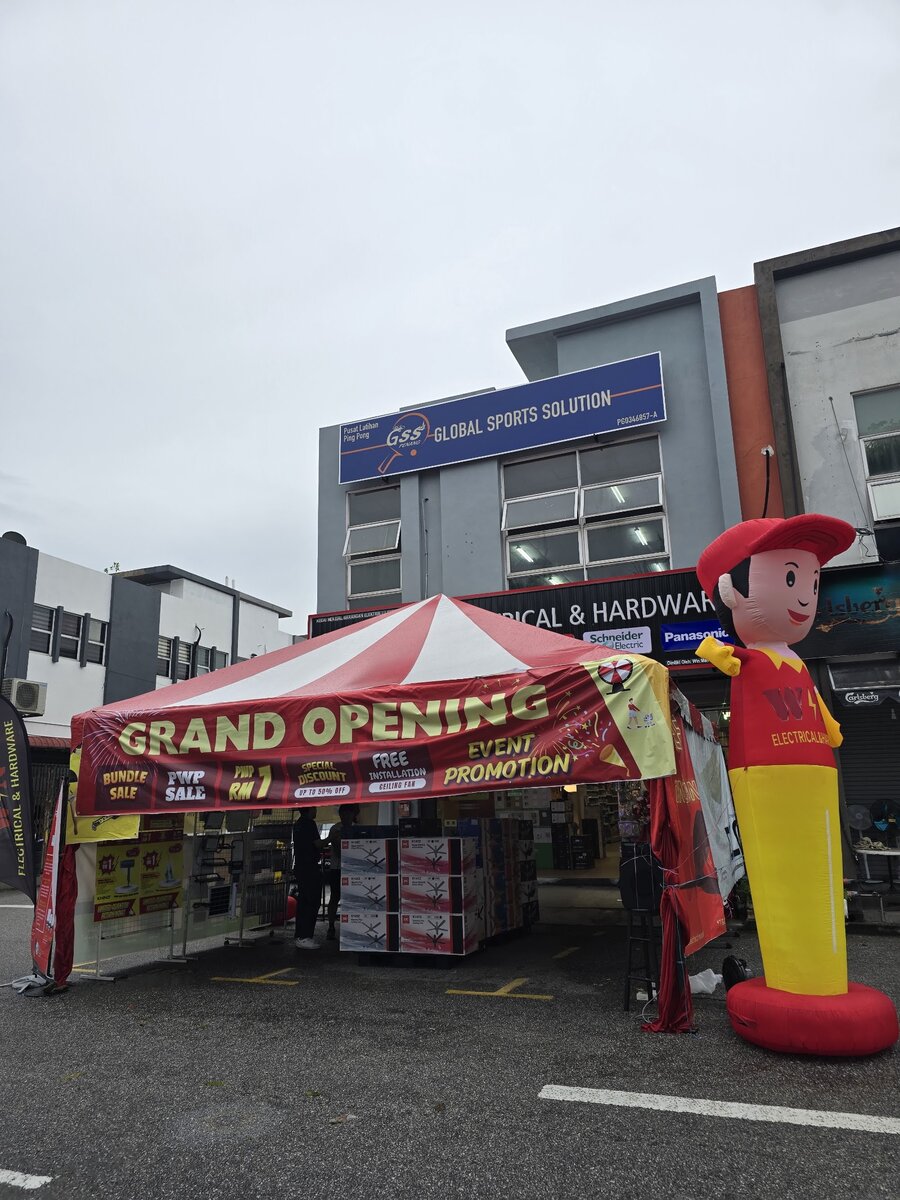Red and white grand opening canopy and an inflatable mascot in front of a shophouse with a WIN Electrical & Hardware signboard carrying Schneider Electric and Panasonic logos