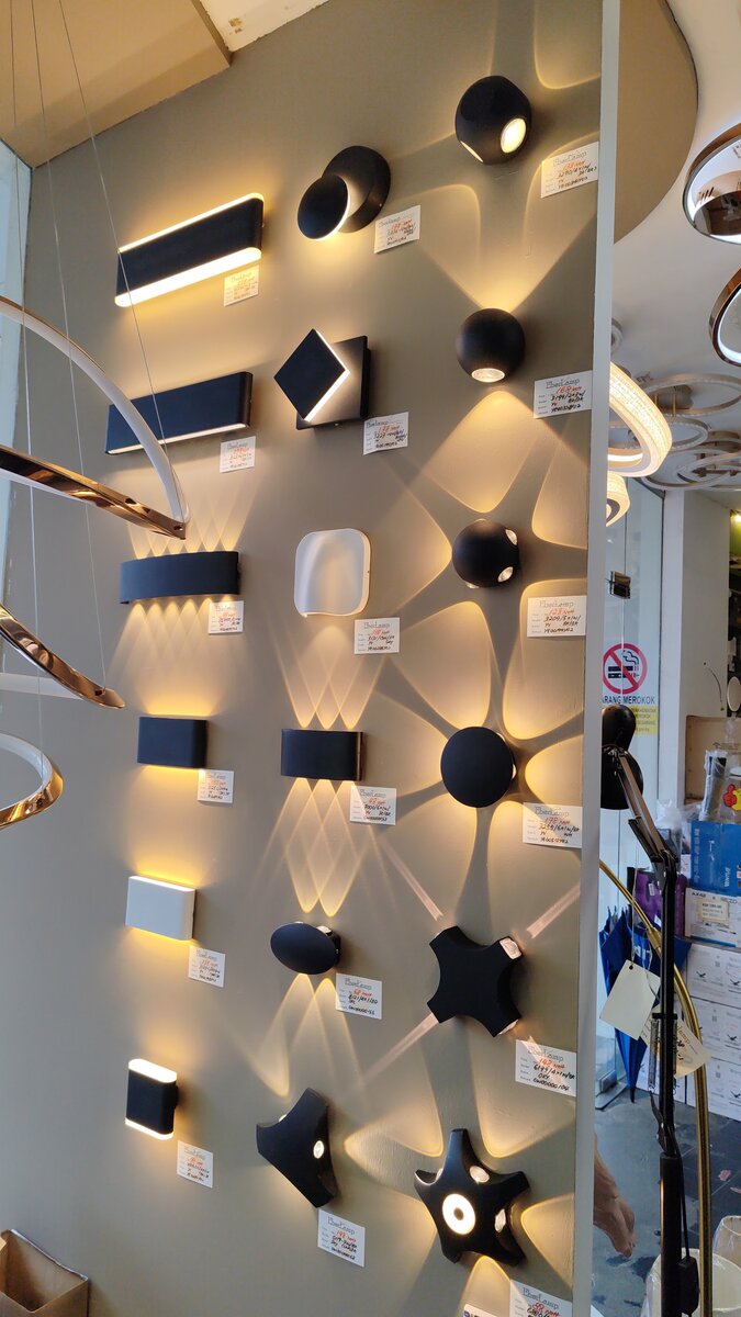Display wall of black and white outdoor-style wall lights casting light patterns, with price tags