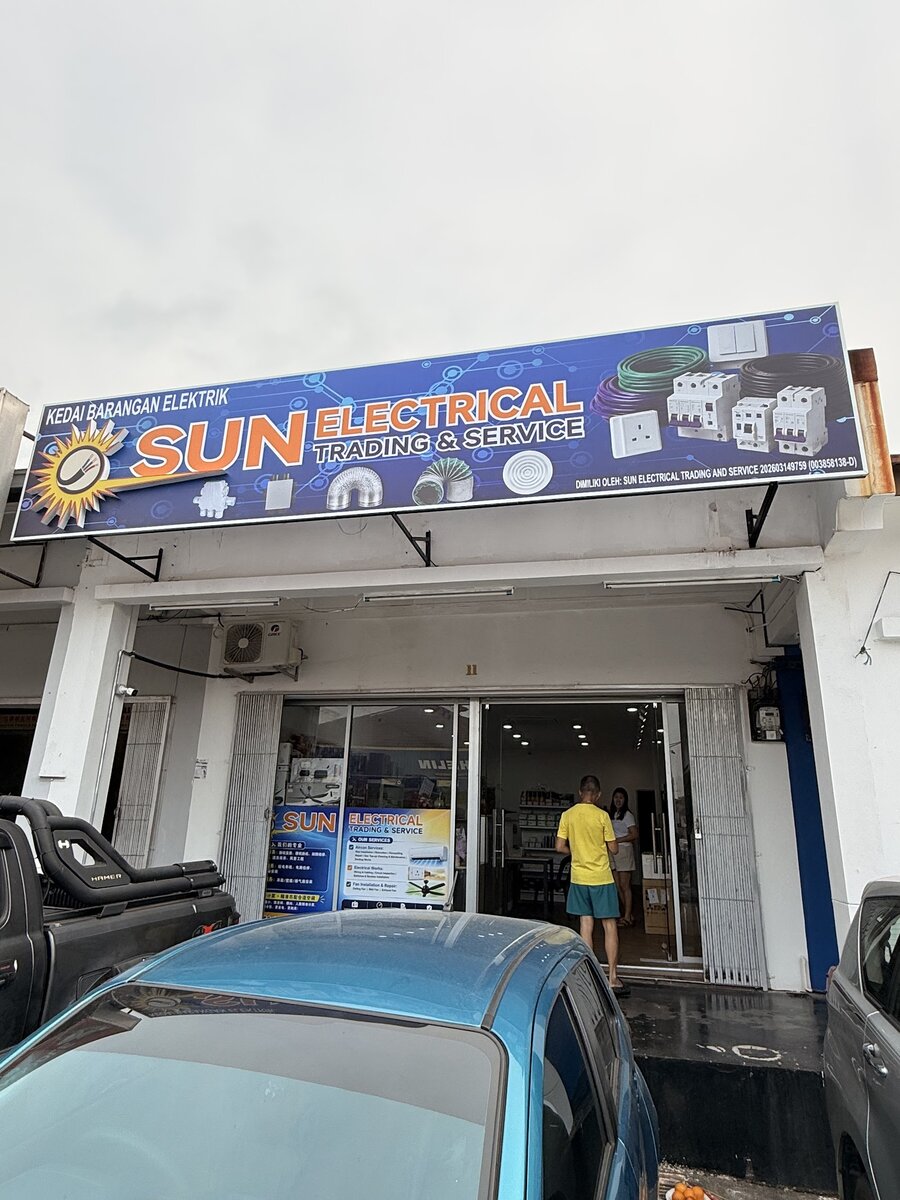Shophouse unit with a blue Sun Electrical Trading & Service signboard showing cable, breakers and sockets above a glass shopfront