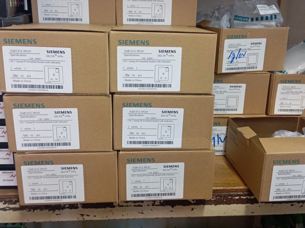 Cardboard boxes labelled Siemens Delta relfa 13A switched socket stacked on a shelf