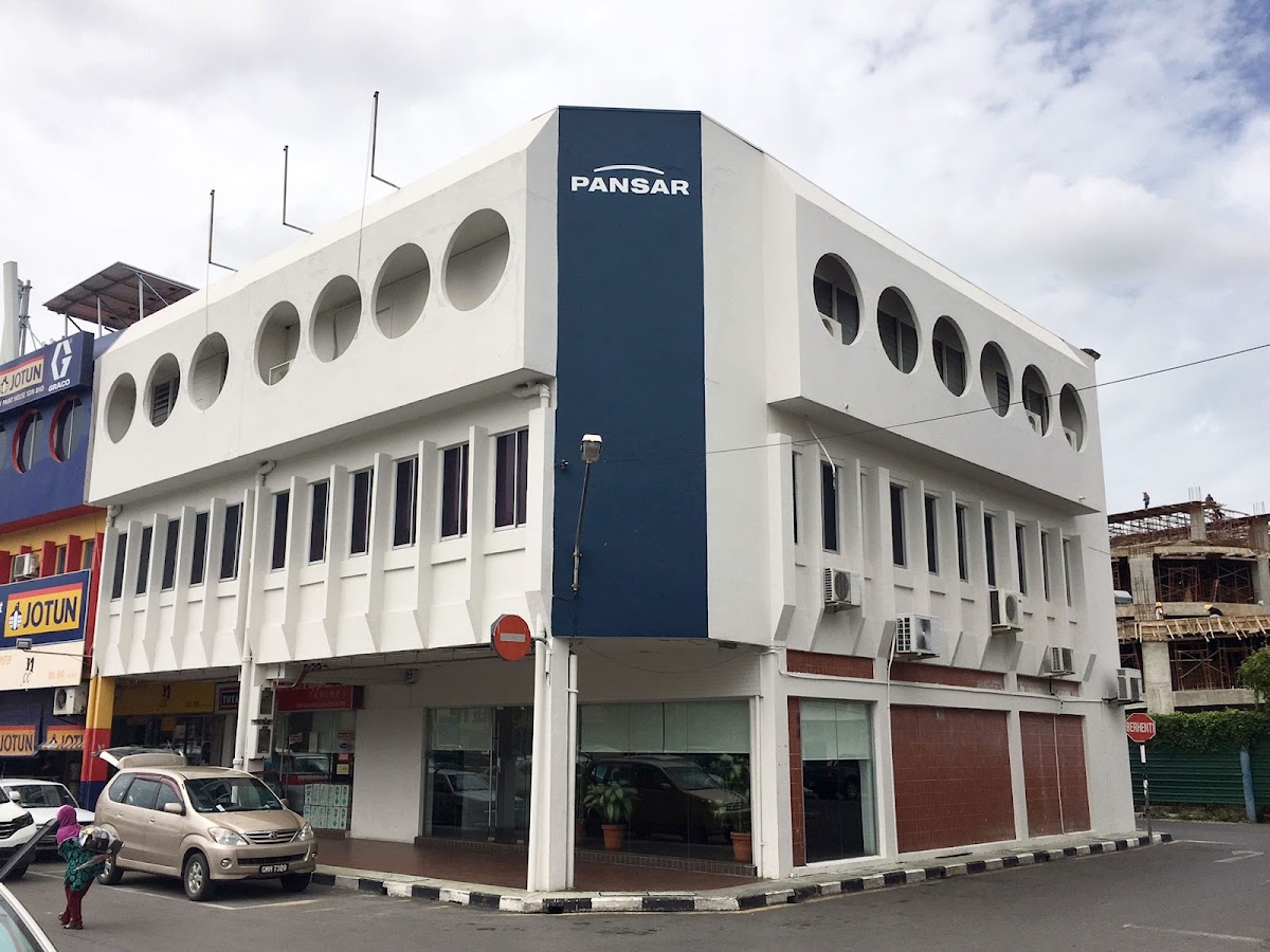 White three-storey corner building with round windows and a tall blue PANSAR panel