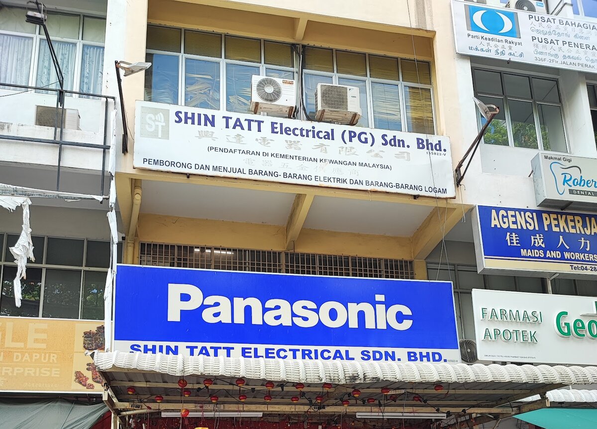 Shophouse front with a white Shin Tatt Electrical signboard and a blue Panasonic signboard above an awning