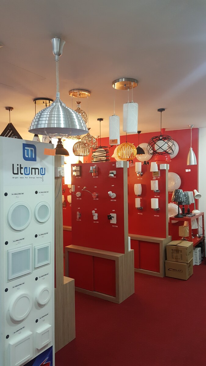 Showroom with hanging pendant lamps, red display walls of wall lights and a white stand of round and square LED downlights