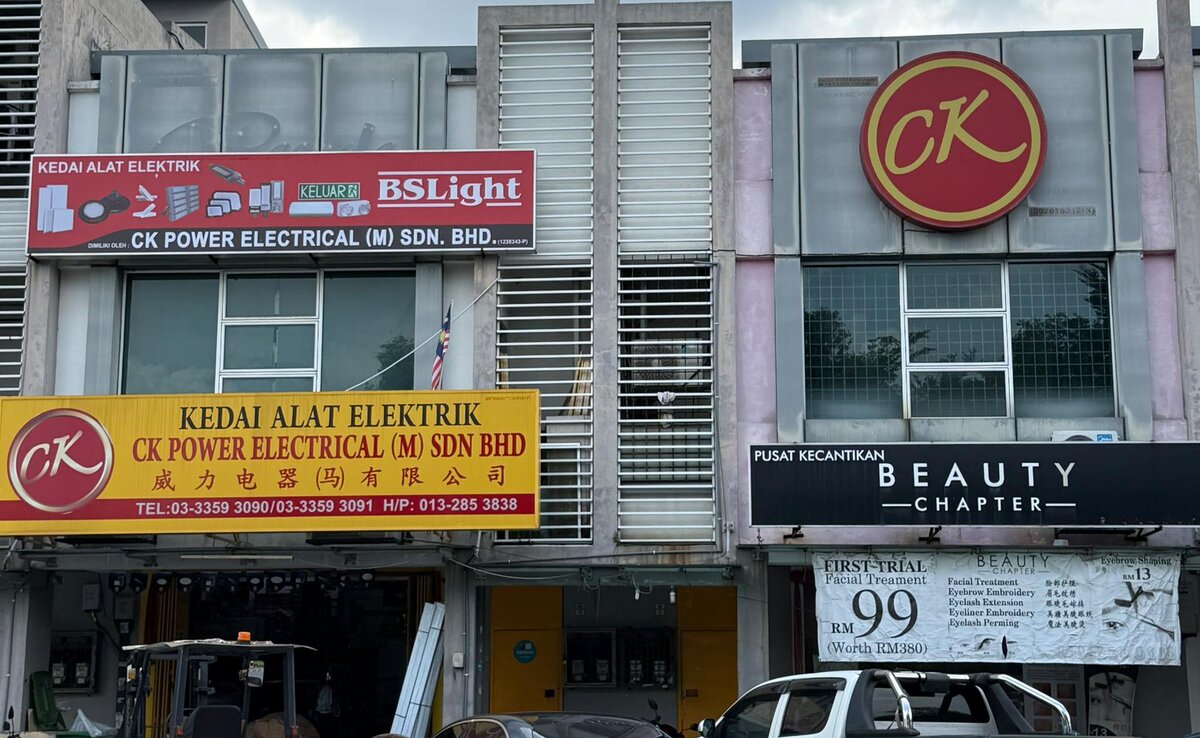Two-storey shop row with a yellow CK Power Electrical signboard in English and Chinese, a red BSLight sign above it, a forklift at the door and a large round CK logo on the neighbouring unit
