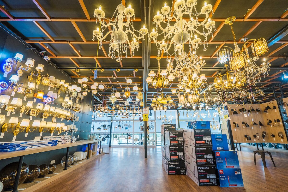 Showroom with rows of crystal chandeliers hanging from a timber-framed ceiling and wall lights along one side