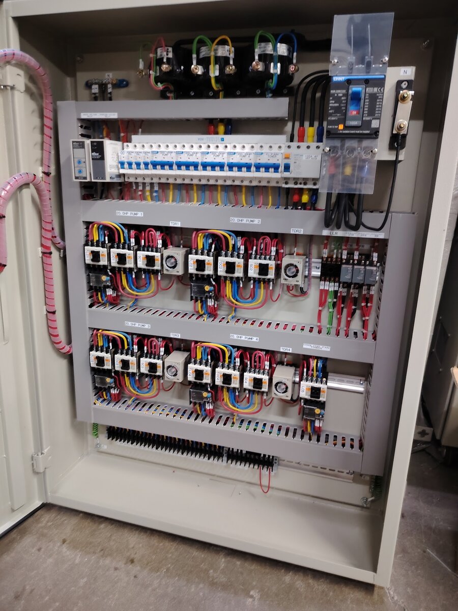 Open grey steel panel wired with rows of contactors, overload relays, modular circuit breakers and terminal blocks