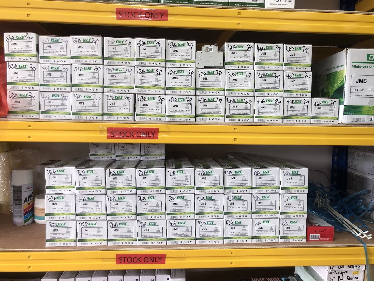 Shelves of white and green EPS JMS breaker boxes with handwritten ratings such as 63A 2P and 40A 3P