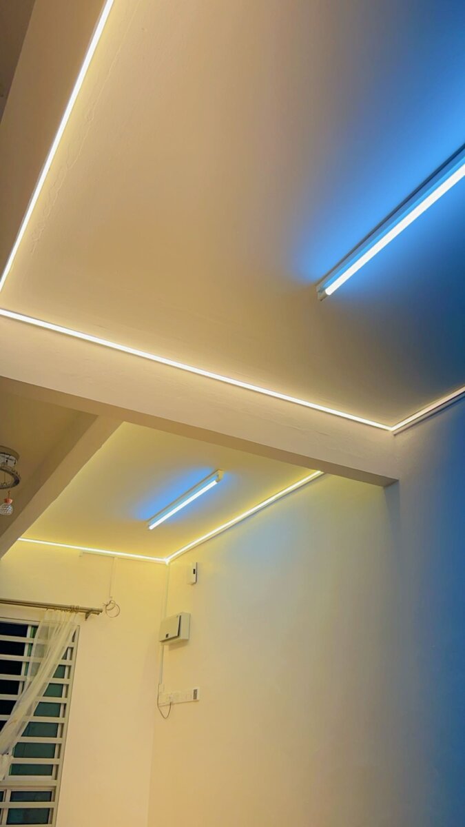 Ceiling with warm-white LED strip lighting along recessed edges and two tube lights casting blue light