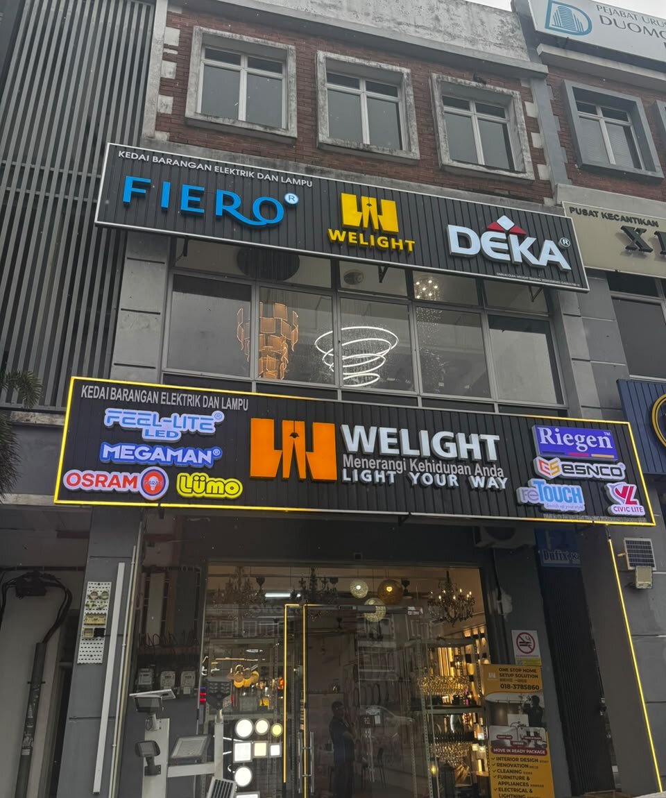 Shopfront with two black signboards reading "Kedai Barangan Elektrik dan Lampu" and "Welight", with Fiero, Deka, Feel-Lite, Megaman, Osram and Riegen logos and lamps behind the glass