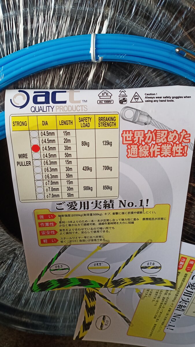 Coil of blue wire puller in plastic wrap with a label table of diameters, lengths and breaking strengths and Japanese text