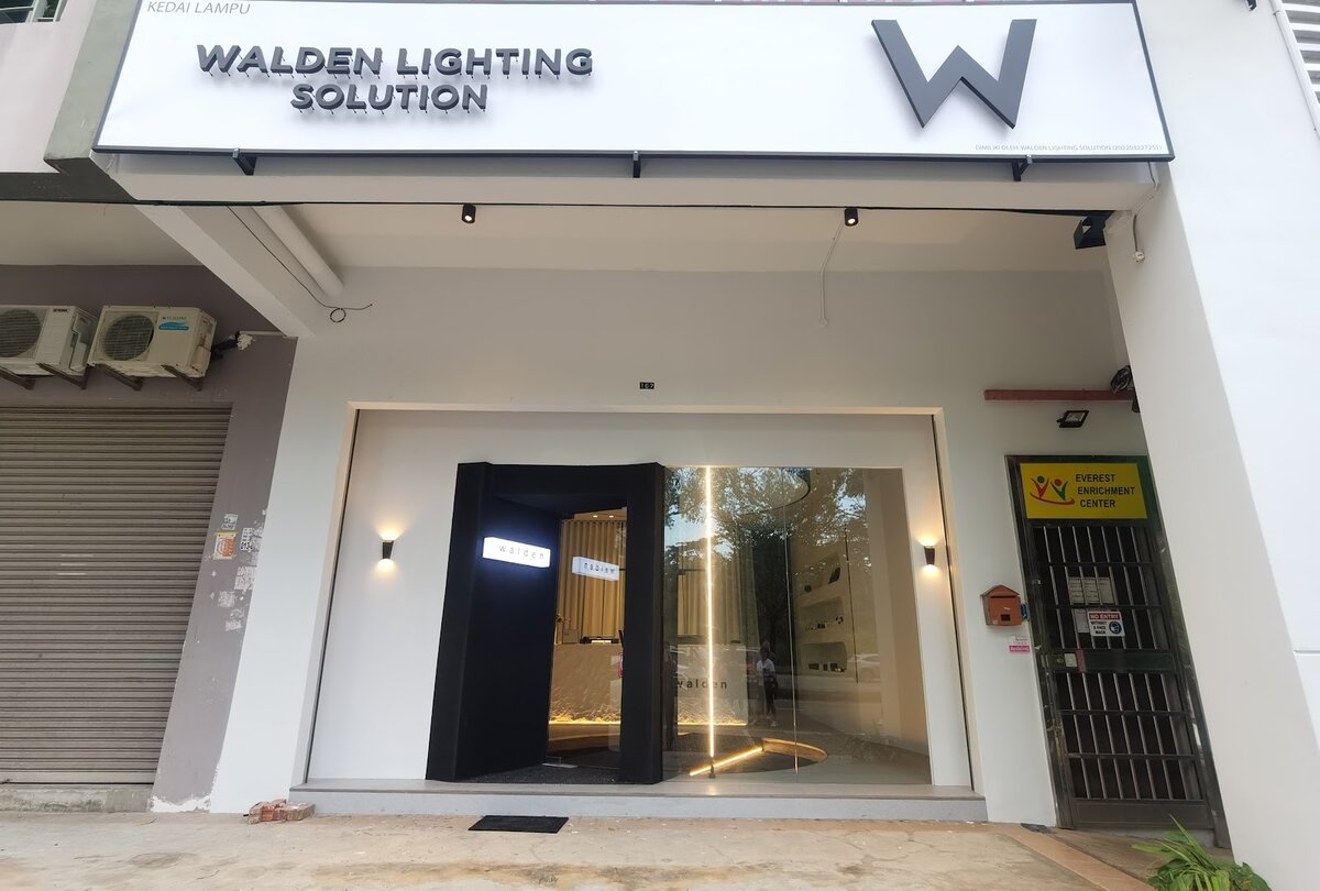 White shopfront with a "Walden Lighting Solution" signboard, a pivoting black door and wall lights either side