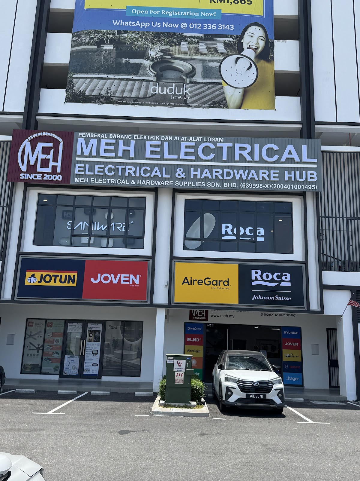 Ground floor of a new commercial block with an MEH Electrical & Hardware Hub signboard and Roca, Saniware, Jotun, Joven and AireGard signs