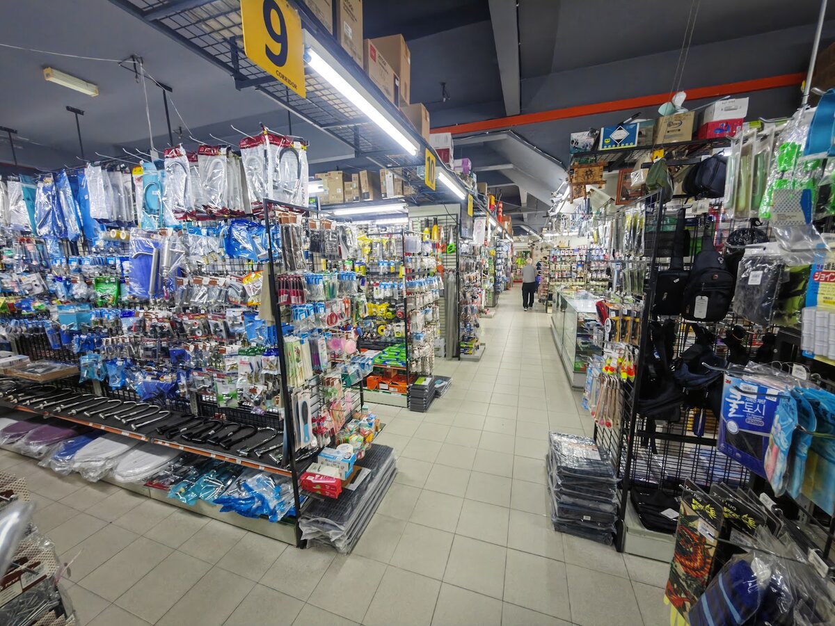Wide shop floor with numbered aisle signs, pegboard displays of tools and packaged accessories, and shelves of household goods