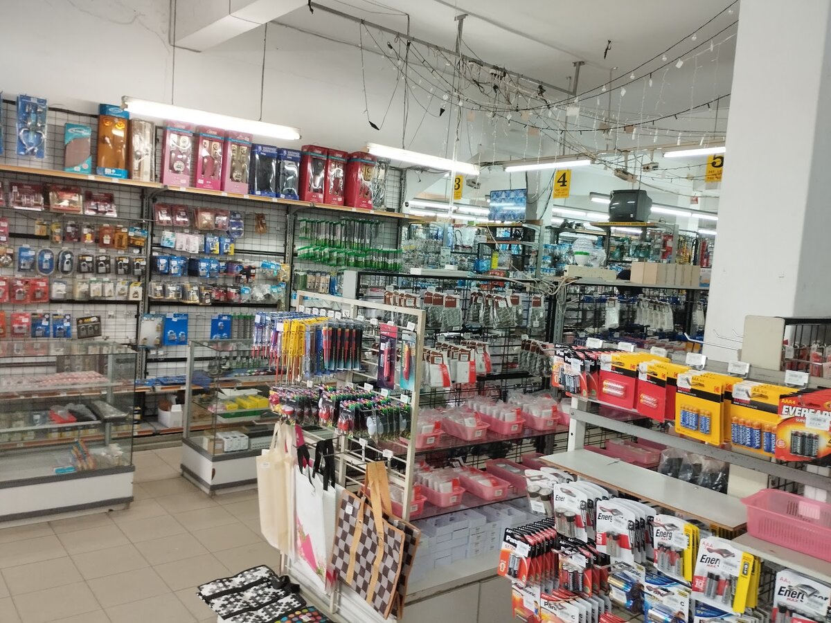 Shop interior with glass display counters, pegboard racks of packaged tools and accessories, and boxes of batteries