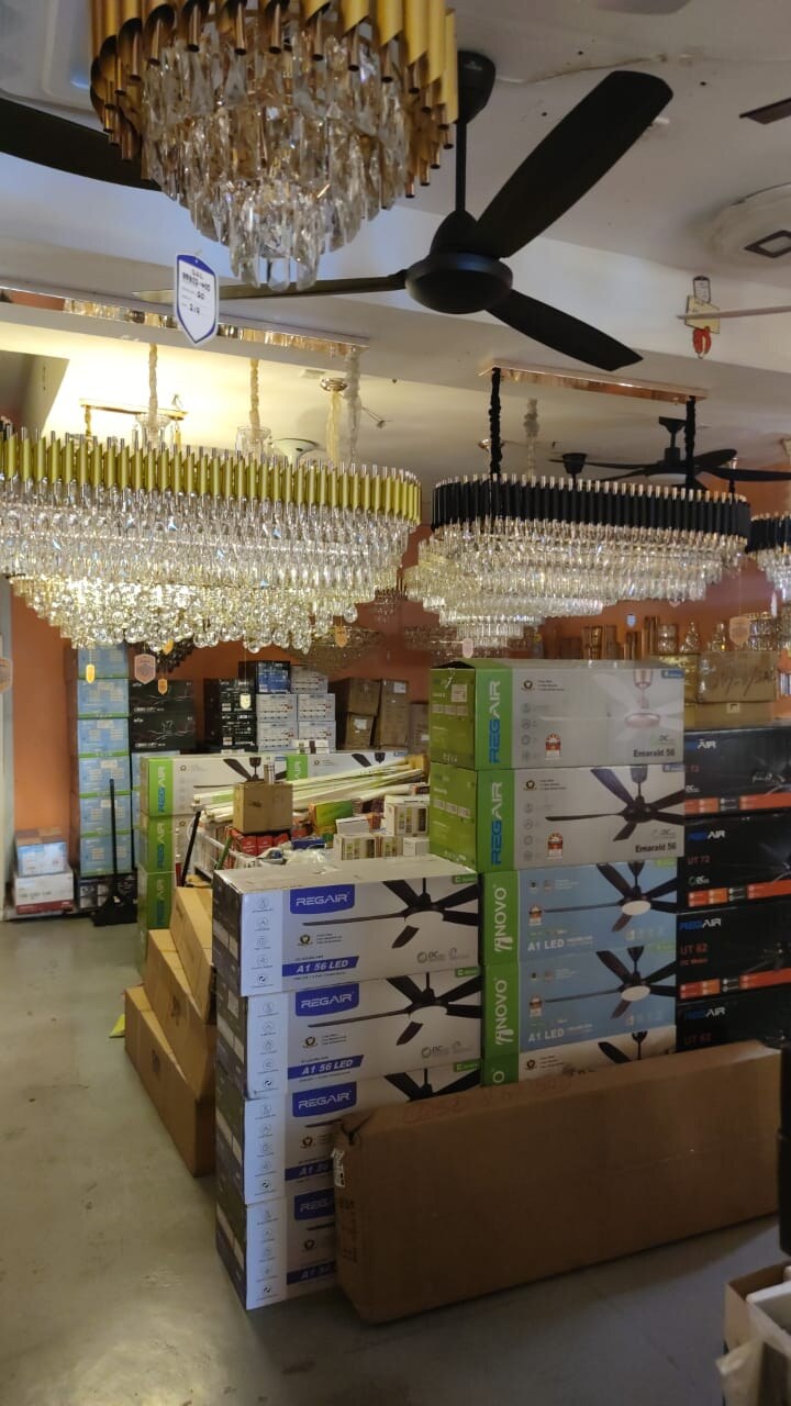 Stacks of ceiling-fan boxes labelled Regair and Novo under hanging crystal chandeliers