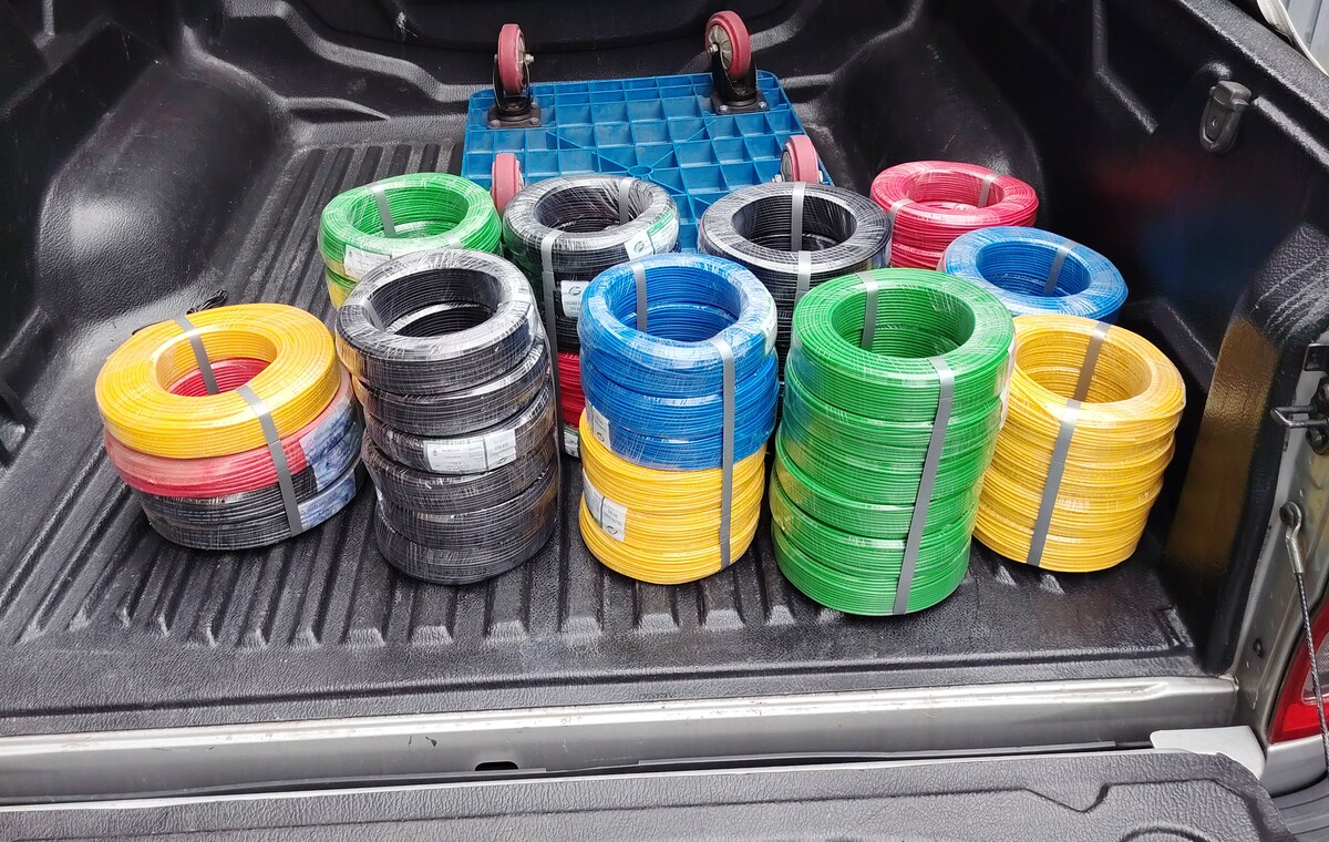 Coils of yellow, black, blue, green and red electrical cable wrapped in plastic in the bed of a pickup truck
