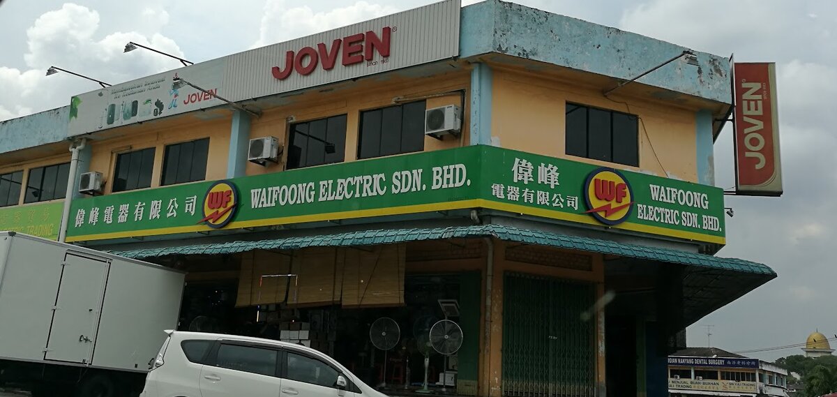 Corner shoplot with a green Waifoong Electric signboard, a red Joven sign on the roof and fans outside