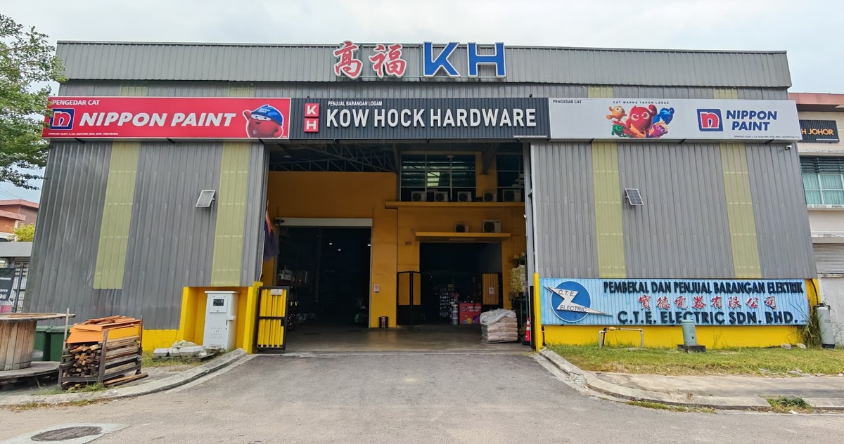 Grey warehouse with Kow Hock Hardware and Nippon Paint signs across the top and a blue C.T.E. Electric Sdn. Bhd. signboard at the lower right of the entrance